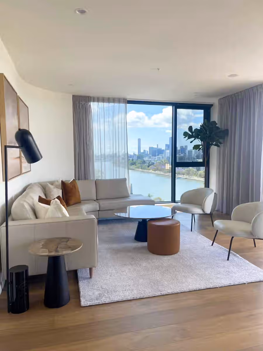 Living room framed by river and city views, with a pale rug and a black arc lamp
