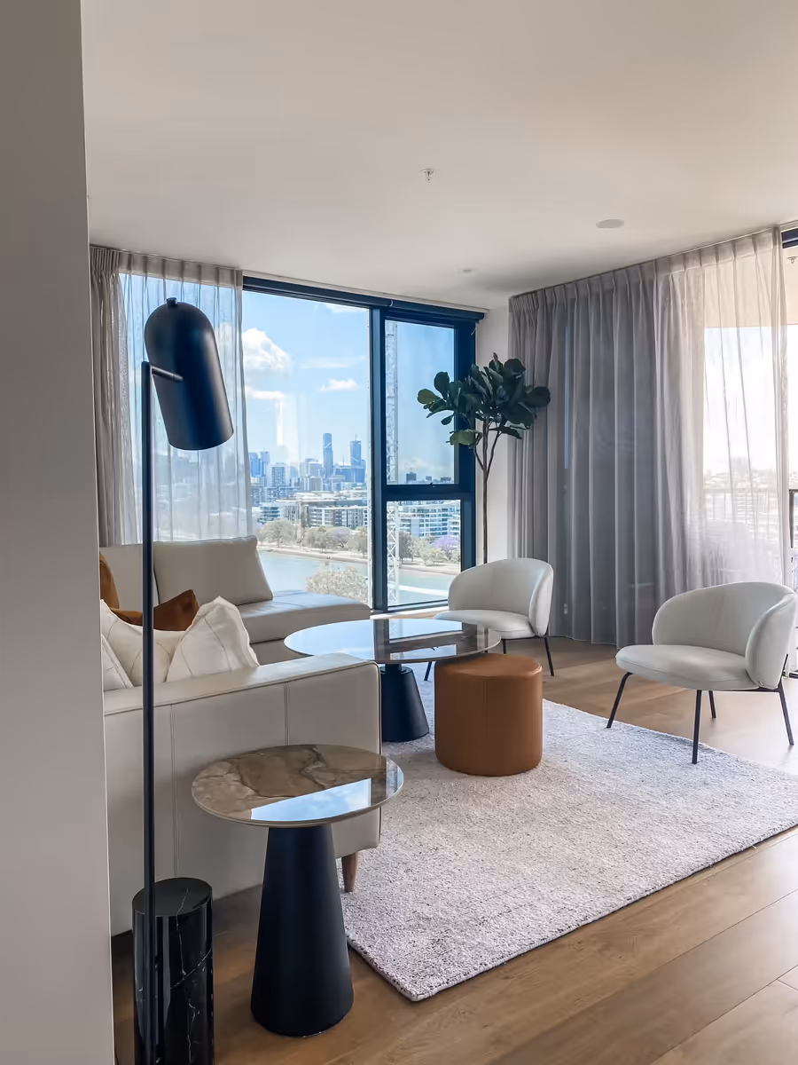 Sheer and grey curtains drawn back from the river view behind the lounge setting