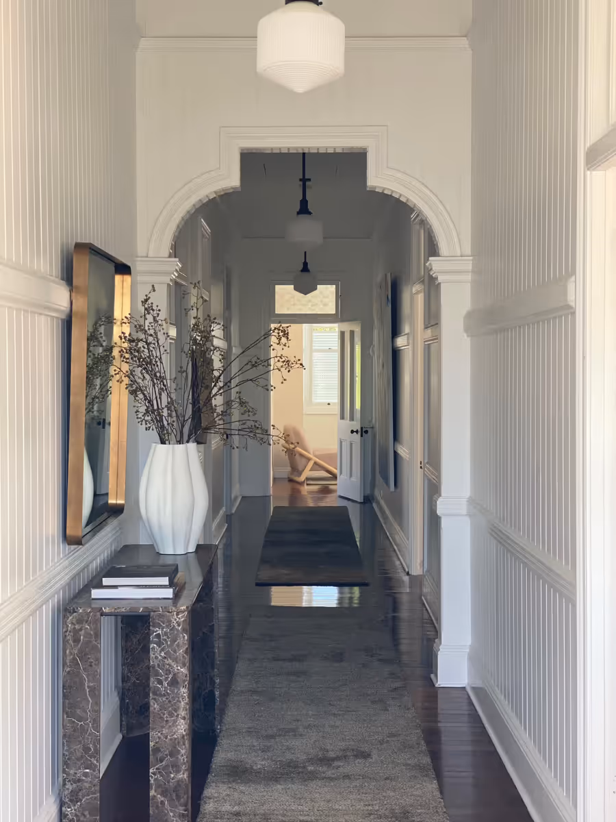 Hallway running through an arched opening, with a dark marble console and a tall white vase