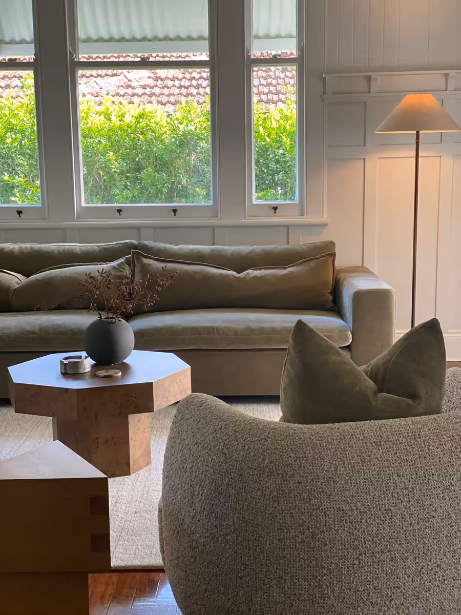 Olive velvet sofa and a chunky timber coffee table in the panelled sitting room