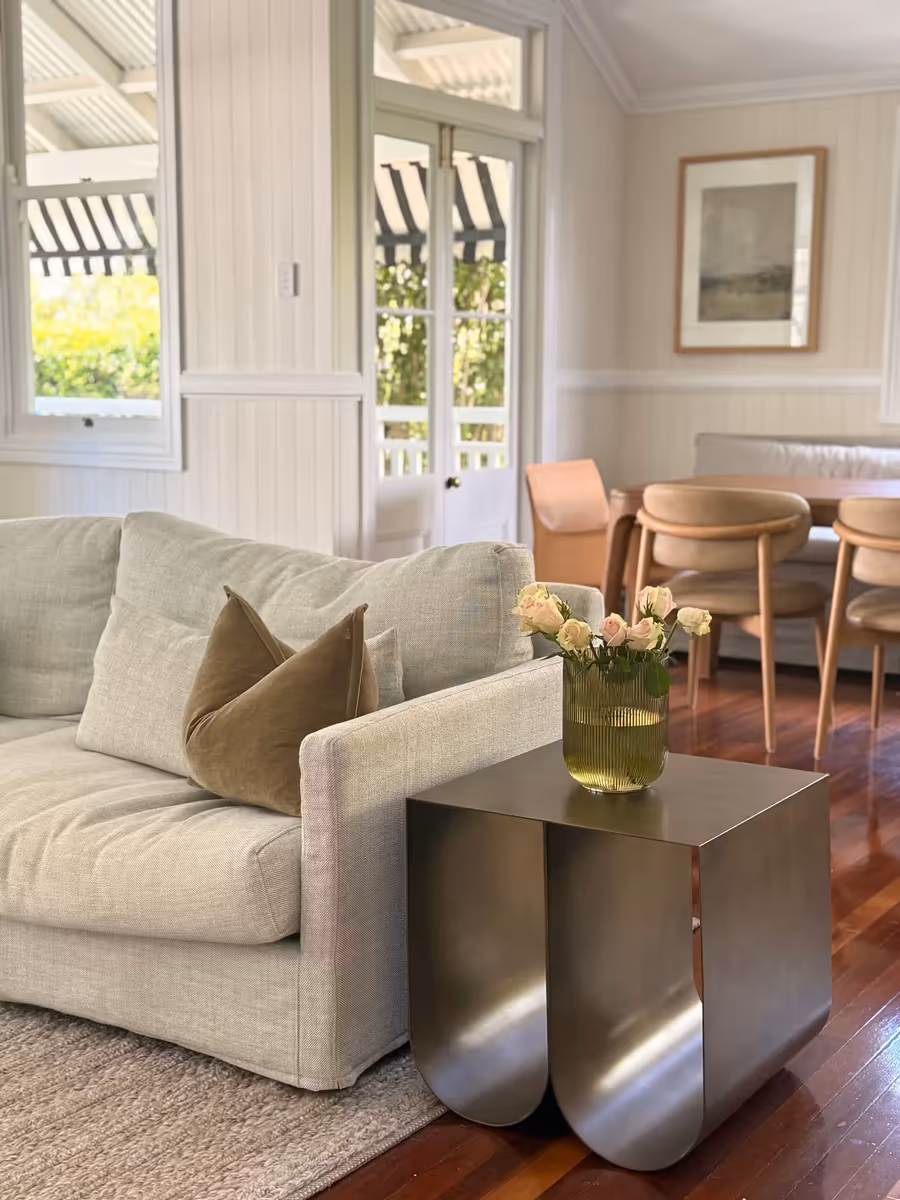 Linen sofa and a curved steel side table on polished dark timber, by the verandah doors