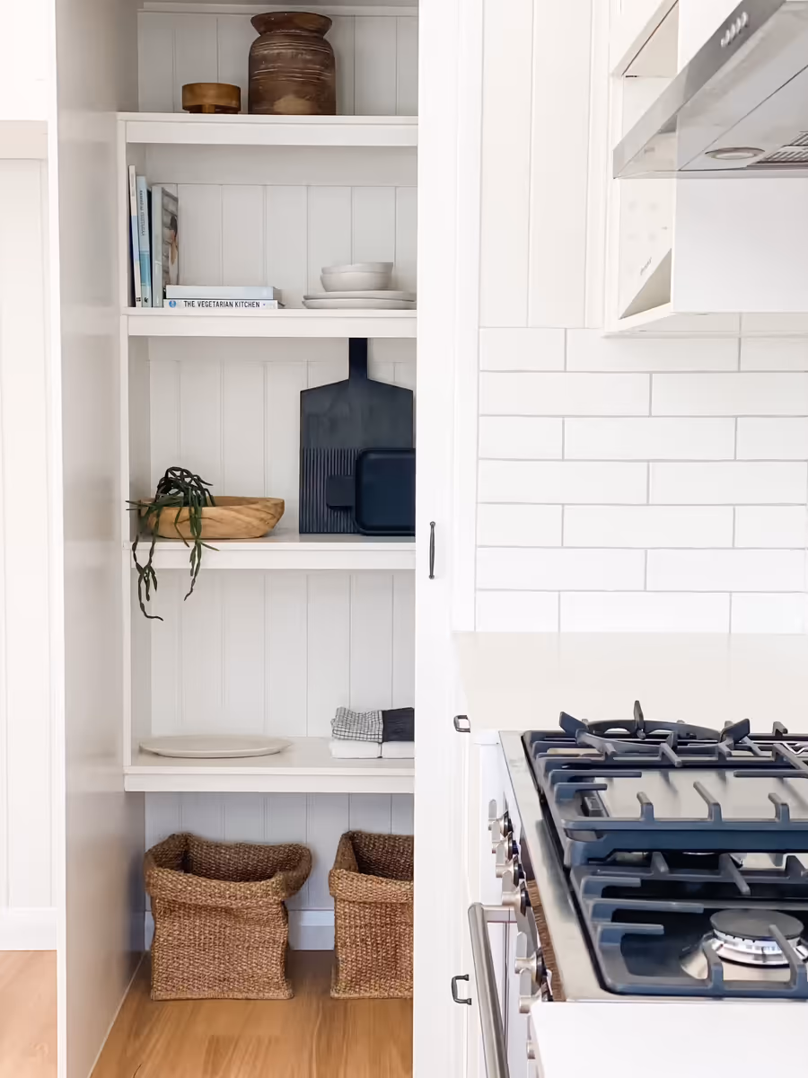 Open shelving beside the cooktop, styled with bowls, boards and woven baskets