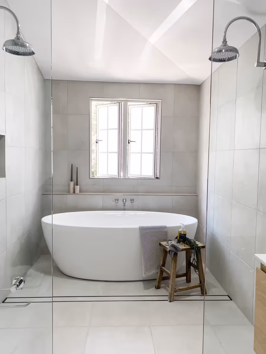 Freestanding bath and walk-in shower in the grey-tiled bathroom