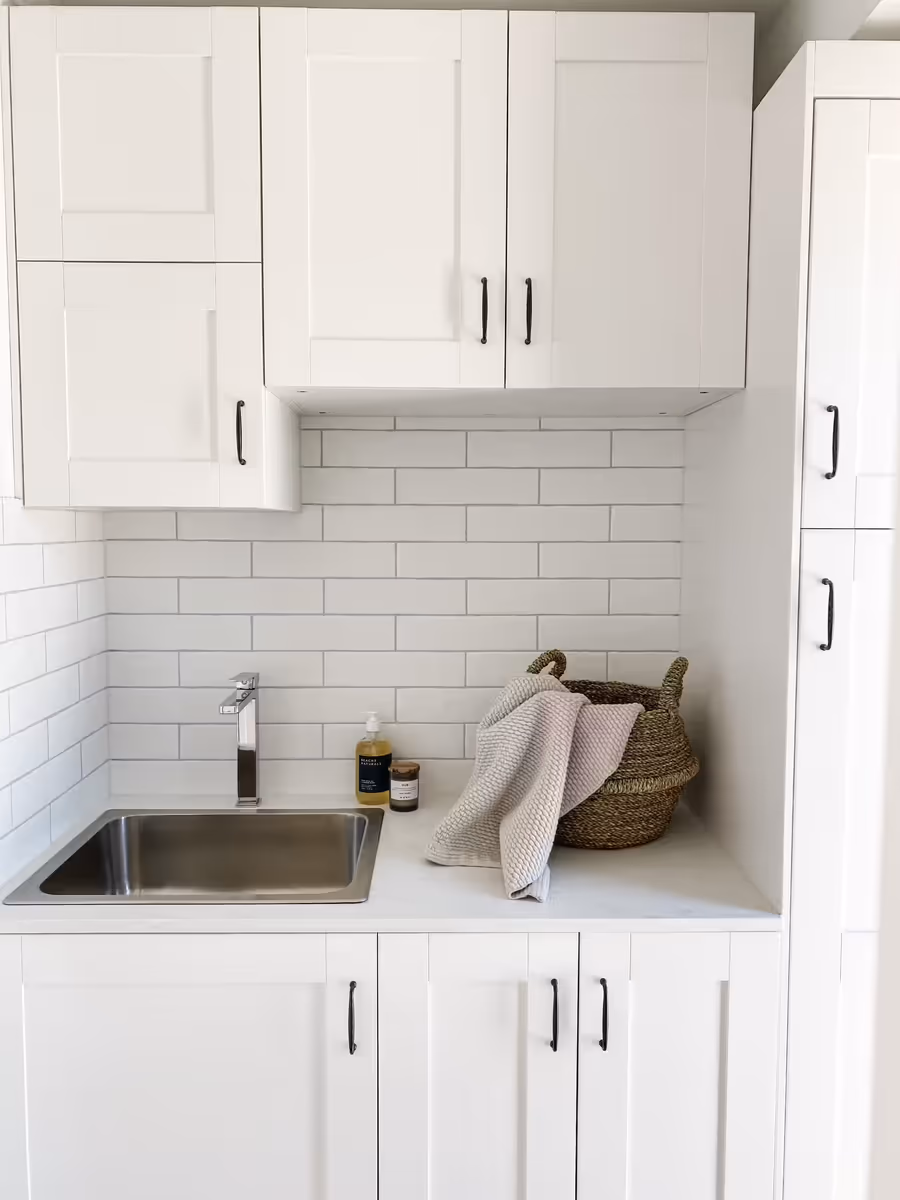 Laundry with white shaker cabinetry, a subway-tiled splashback and a stainless trough