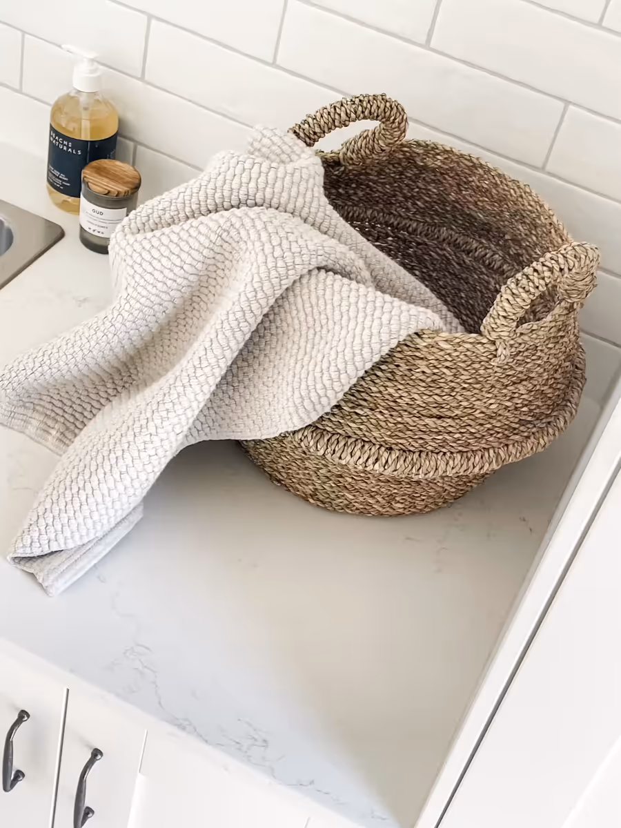 Woven basket and a folded knit throw on the laundry benchtop