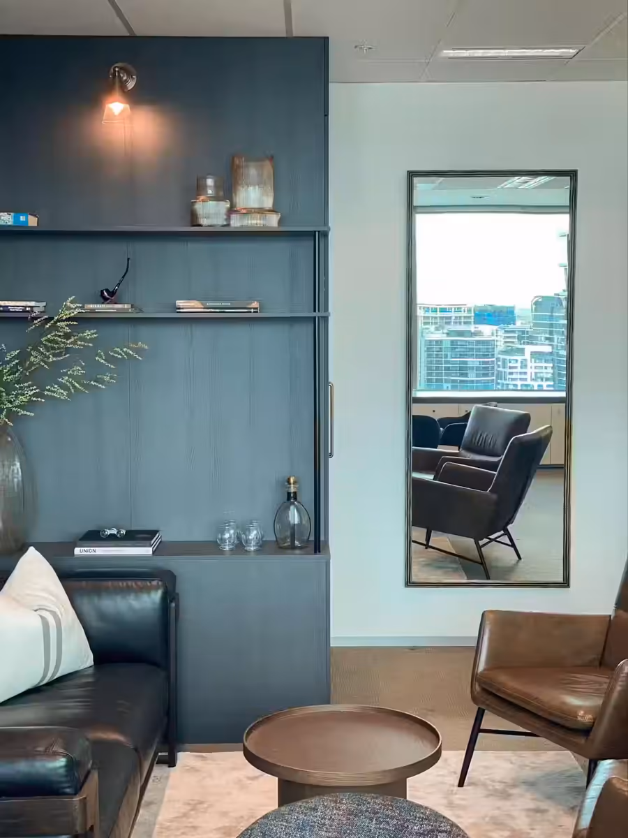 Teal joinery and a black leather sofa in the chambers, with a tan armchair by the city view