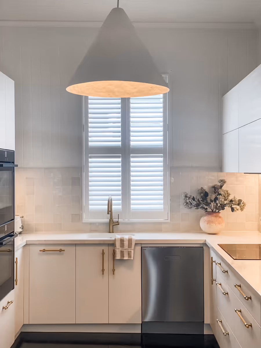 Cream kitchen with brass handles and an oversized pendant hanging above the sink