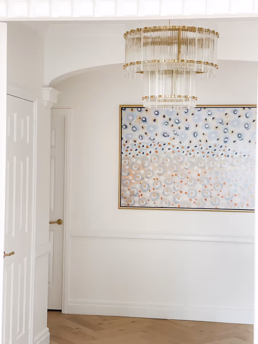 Confetti-patterned canvas below a gilt chandelier in the panelled entry