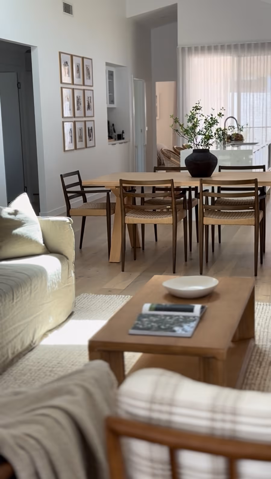 Open plan living and dining, with a low timber coffee table and a framed picture wall