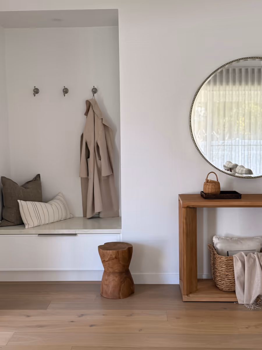 Entry with a built-in bench seat, round mirror and a timber console over a woven basket