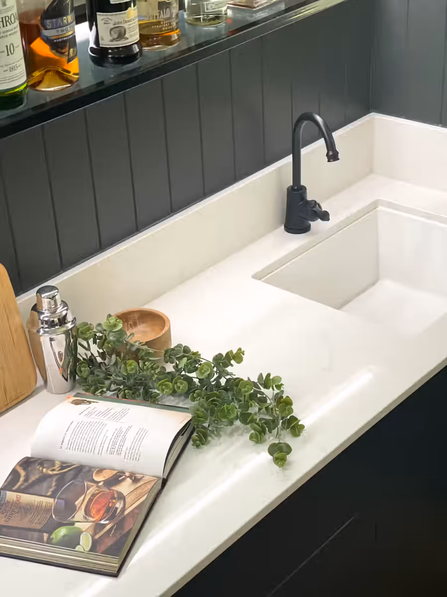 Undermount sink and white stone bar top against dark green panelling