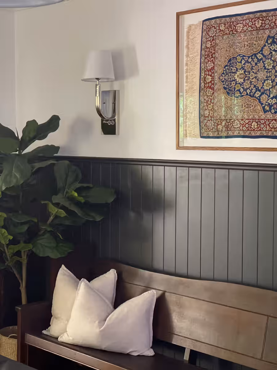 Timber bench seat below a framed Persian rug, beside a fiddle-leaf fig
