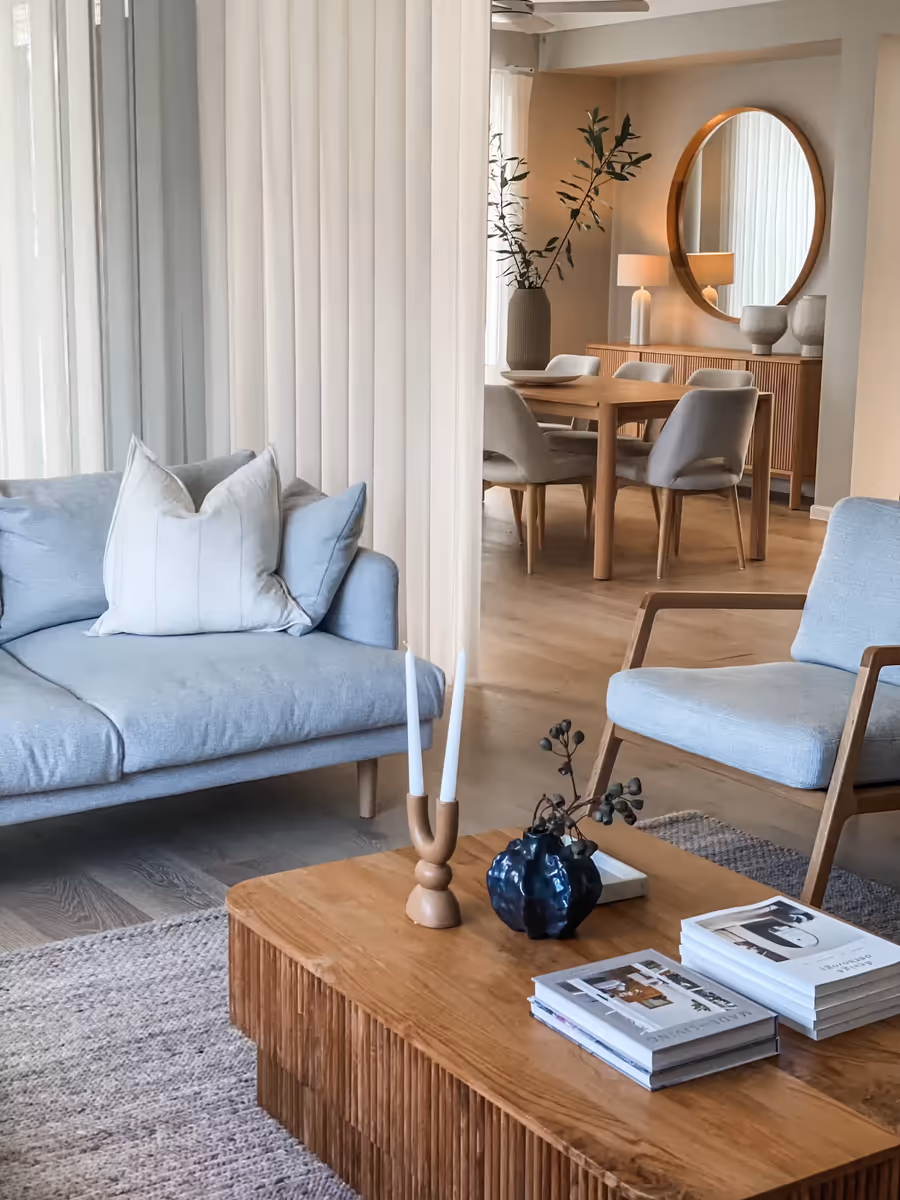Pale blue sofa and armchair around a fluted oak coffee table, the dining room beyond