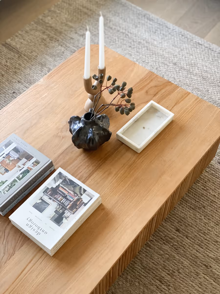Candlesticks, a dark ceramic vase and design books on the fluted oak coffee table