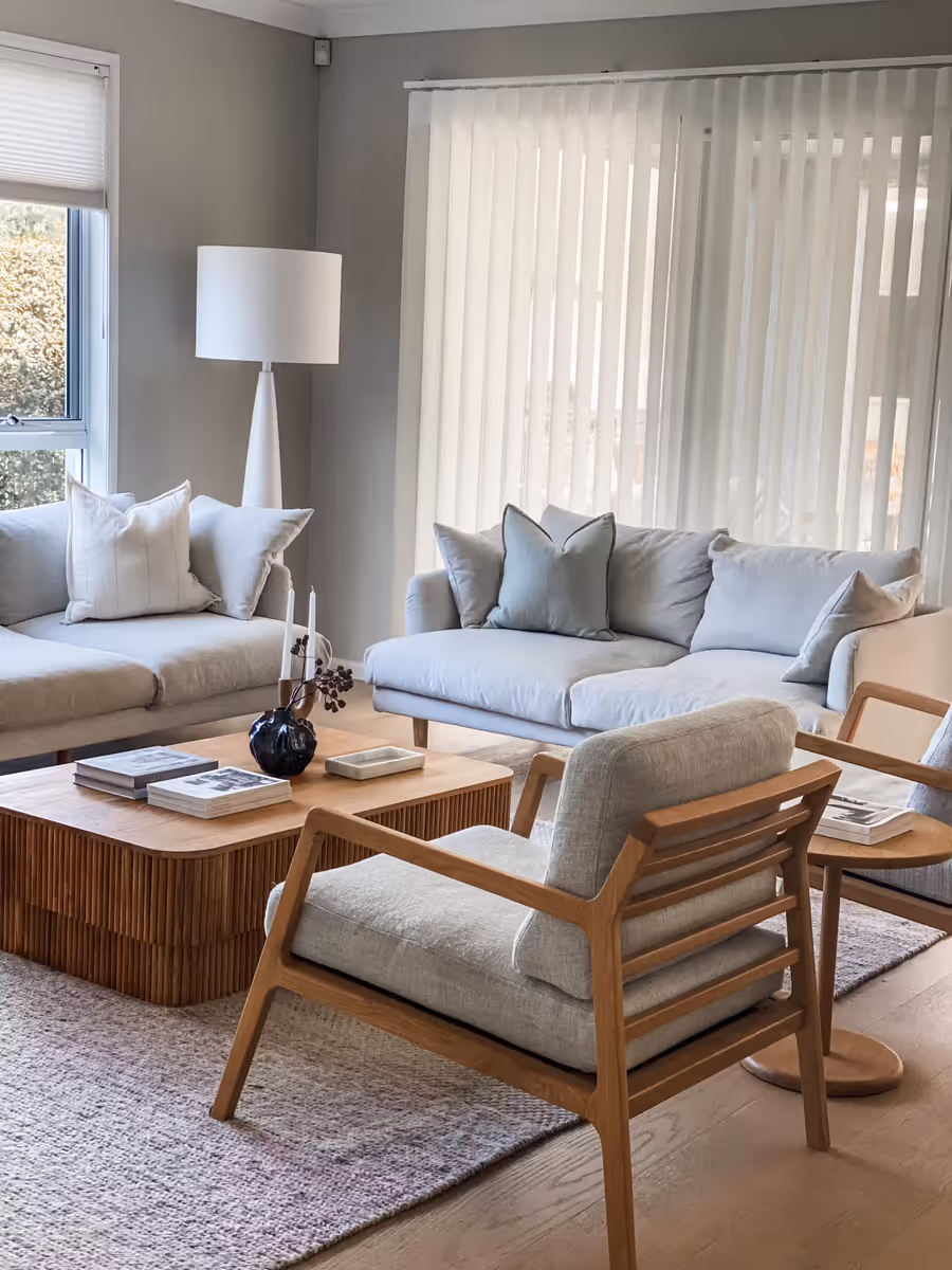 Blue linen sofas and an oak armchair around the fluted coffee table, sheers behind