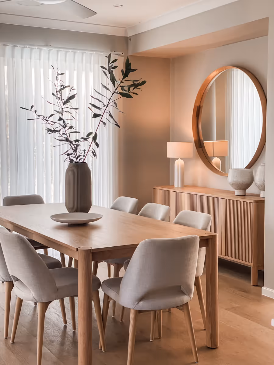 Oak dining table and velvet chairs, with a round mirror above the fluted sideboard