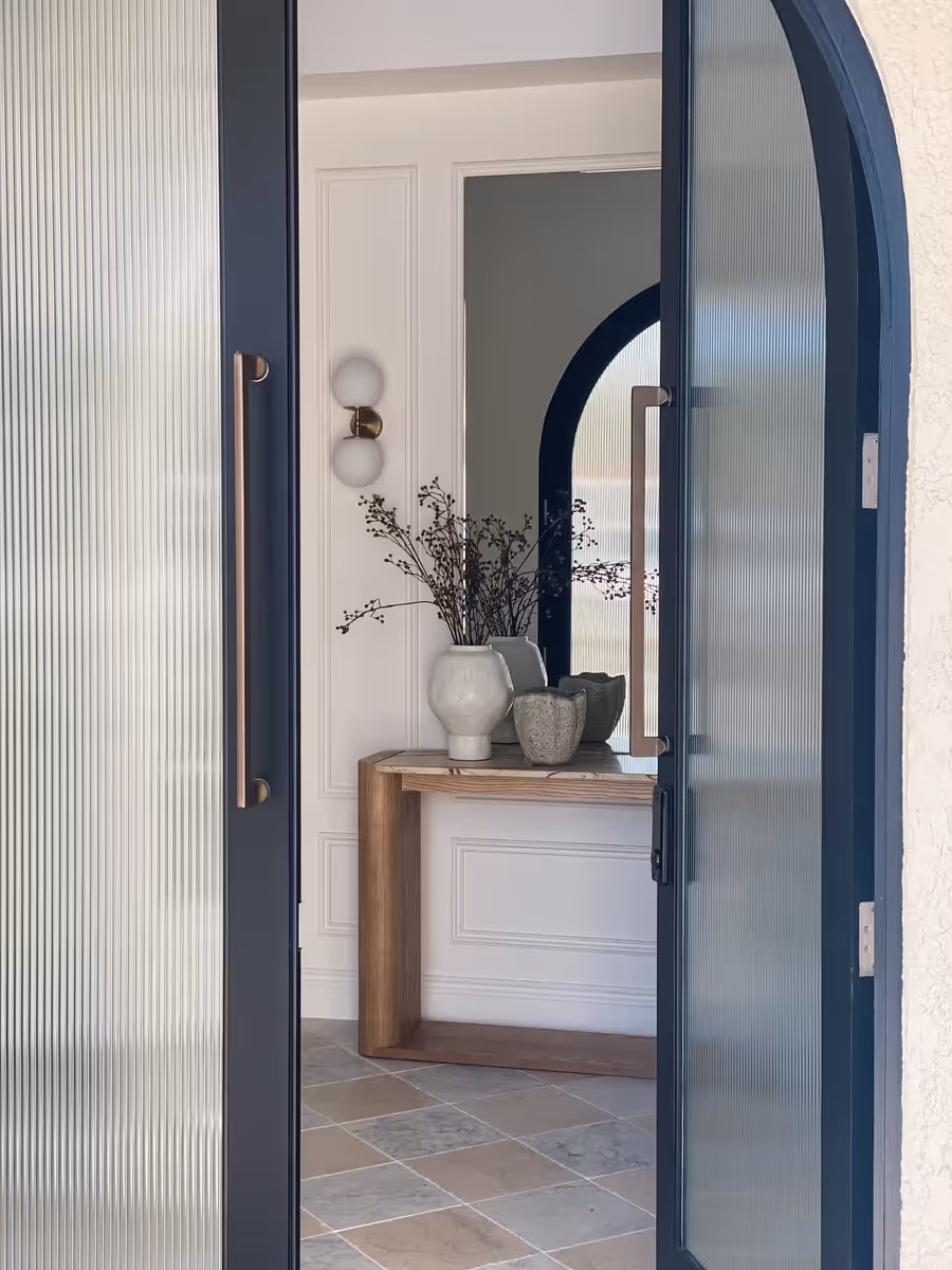Navy arched door and fluted glass framing the entry console and mirror