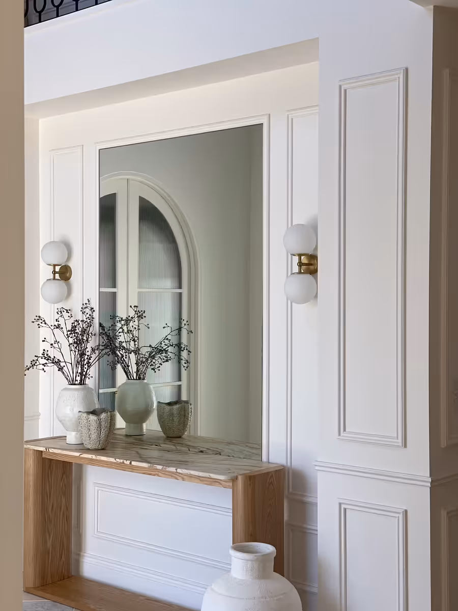 Oak console styled with pale vases below a mirror, in the panelled hallway