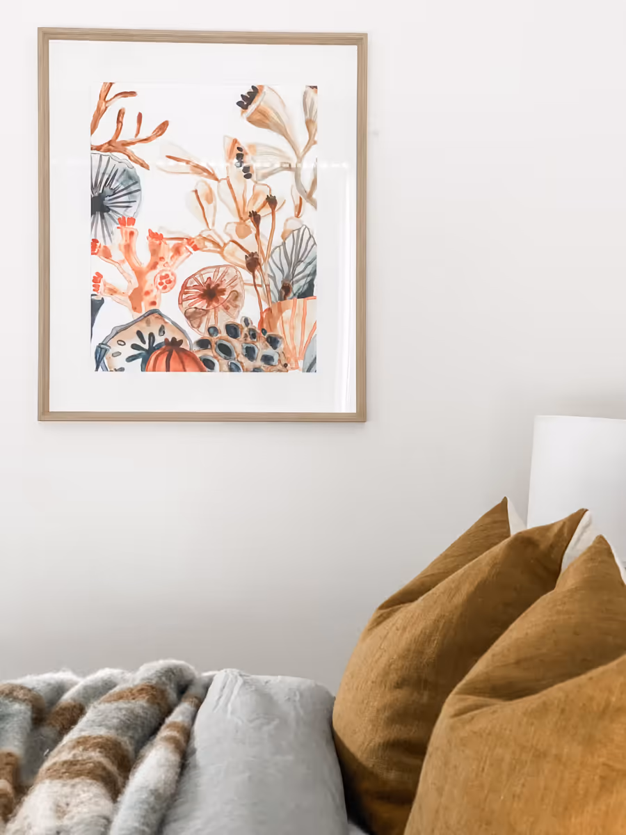 Mustard linen cushions and a checked throw on the sofa, below a botanical print