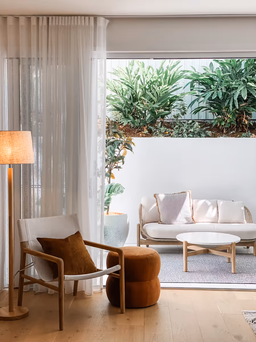 Sling armchair and rust ottoman by the sheer-curtained doors, out to the courtyard lounge