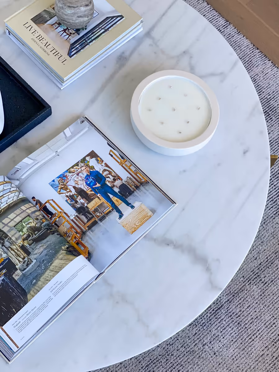 Open design book and a wide candle on the marble coffee table