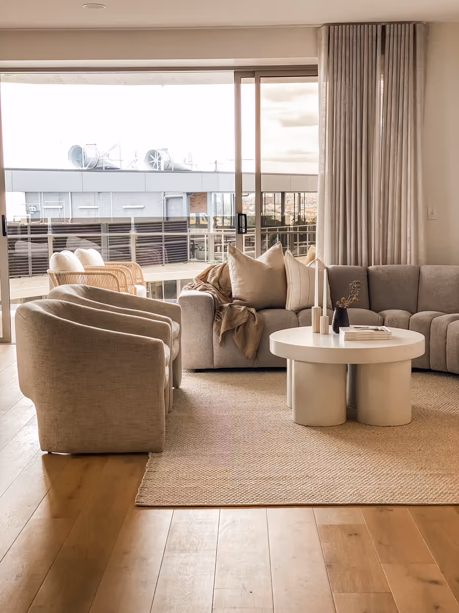 Grey modular sofa and swivel chairs on a jute rug, opening to the balcony