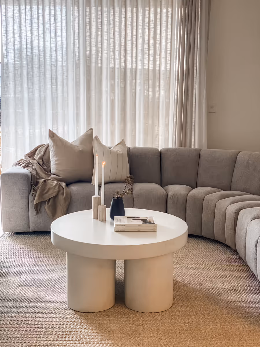Curved grey modular sofa around a chunky white round coffee table