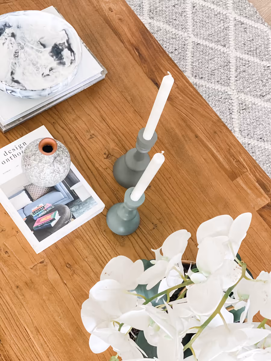 Candlesticks, a speckled vase and design books arranged on the oak dining table