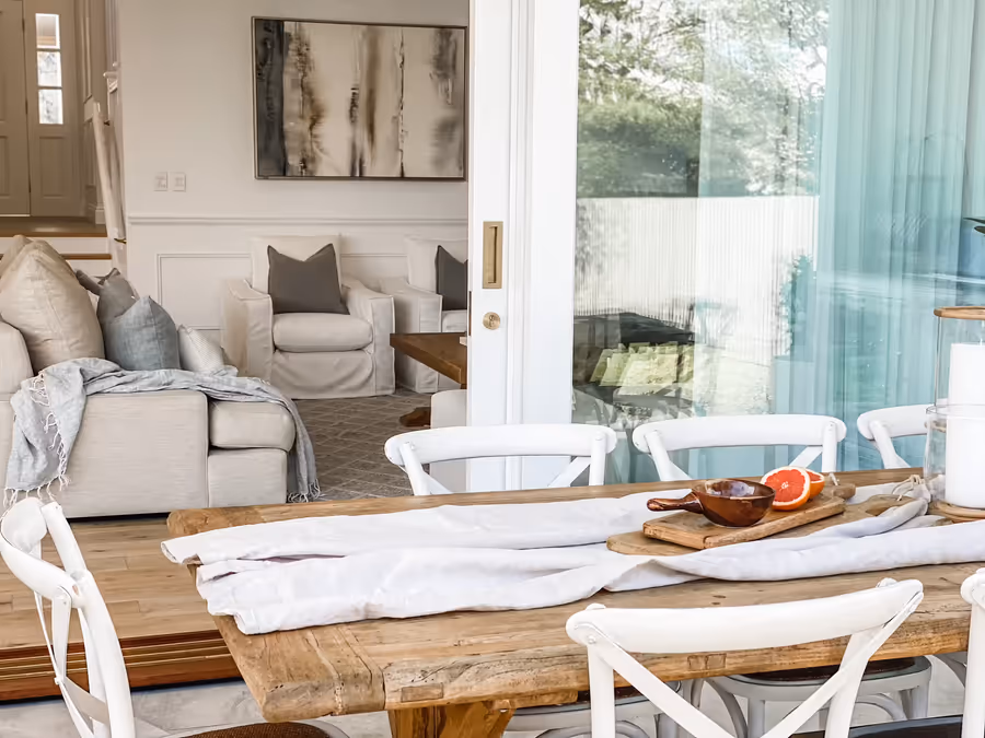 Long timber dining table set with a runner and board, the living room behind
