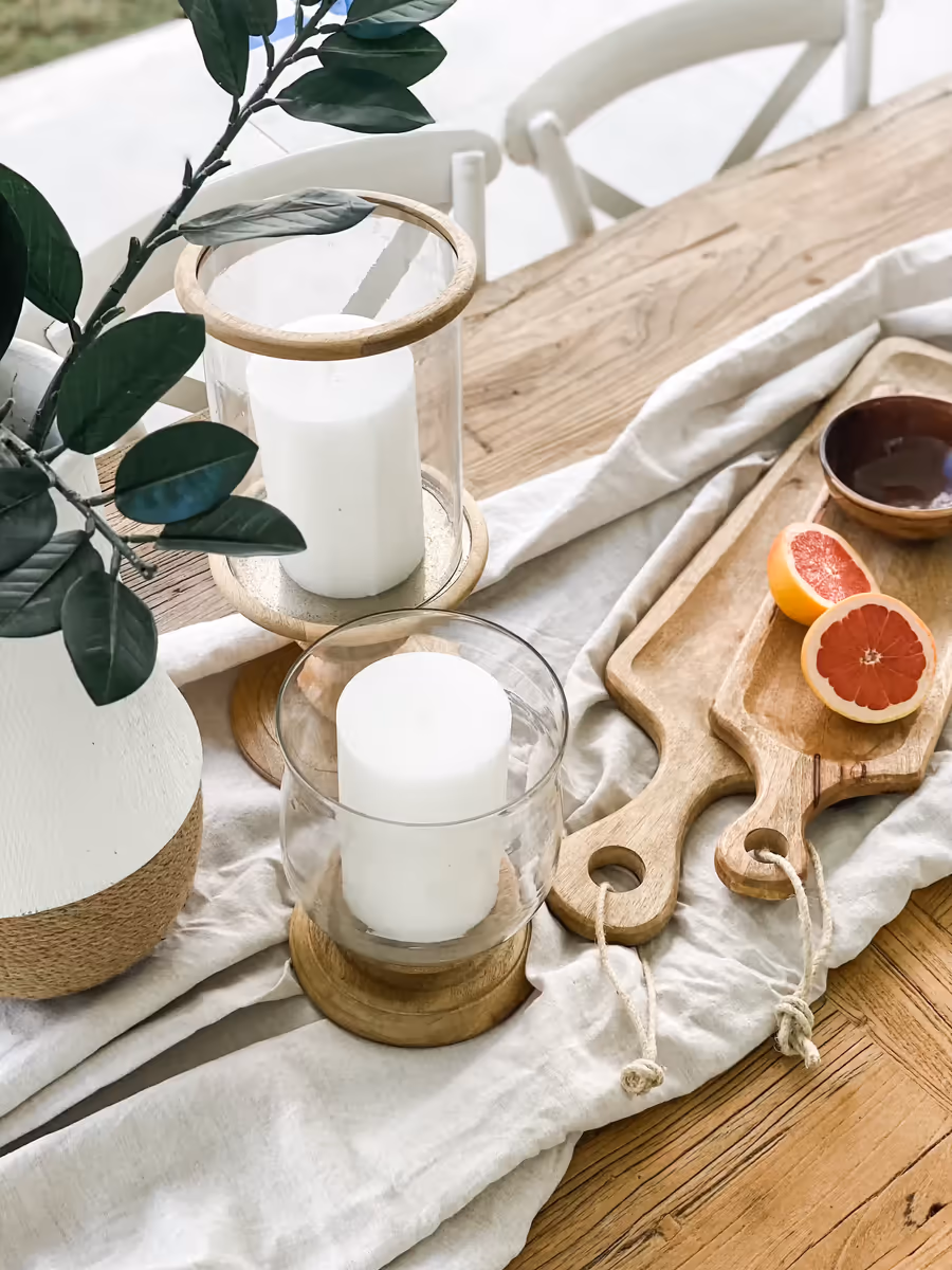 Hurricane candles and a grapefruit-topped board on the timber table runner
