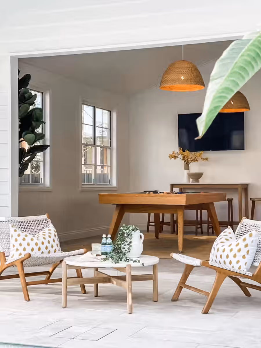 Sling chairs around a low table on the pool terrace, games room beyond