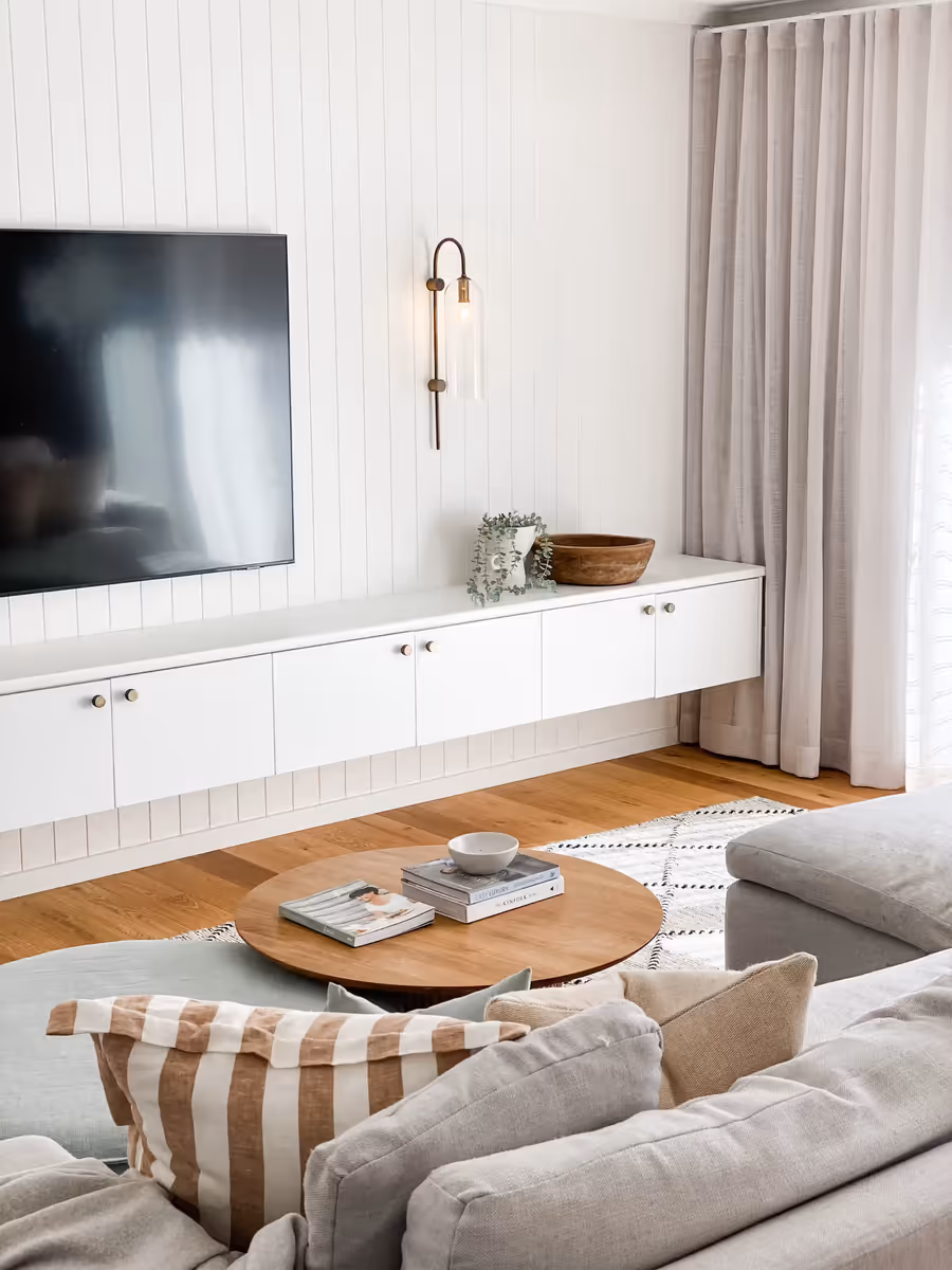Linen sofa and a round oak coffee table facing the panelled media wall