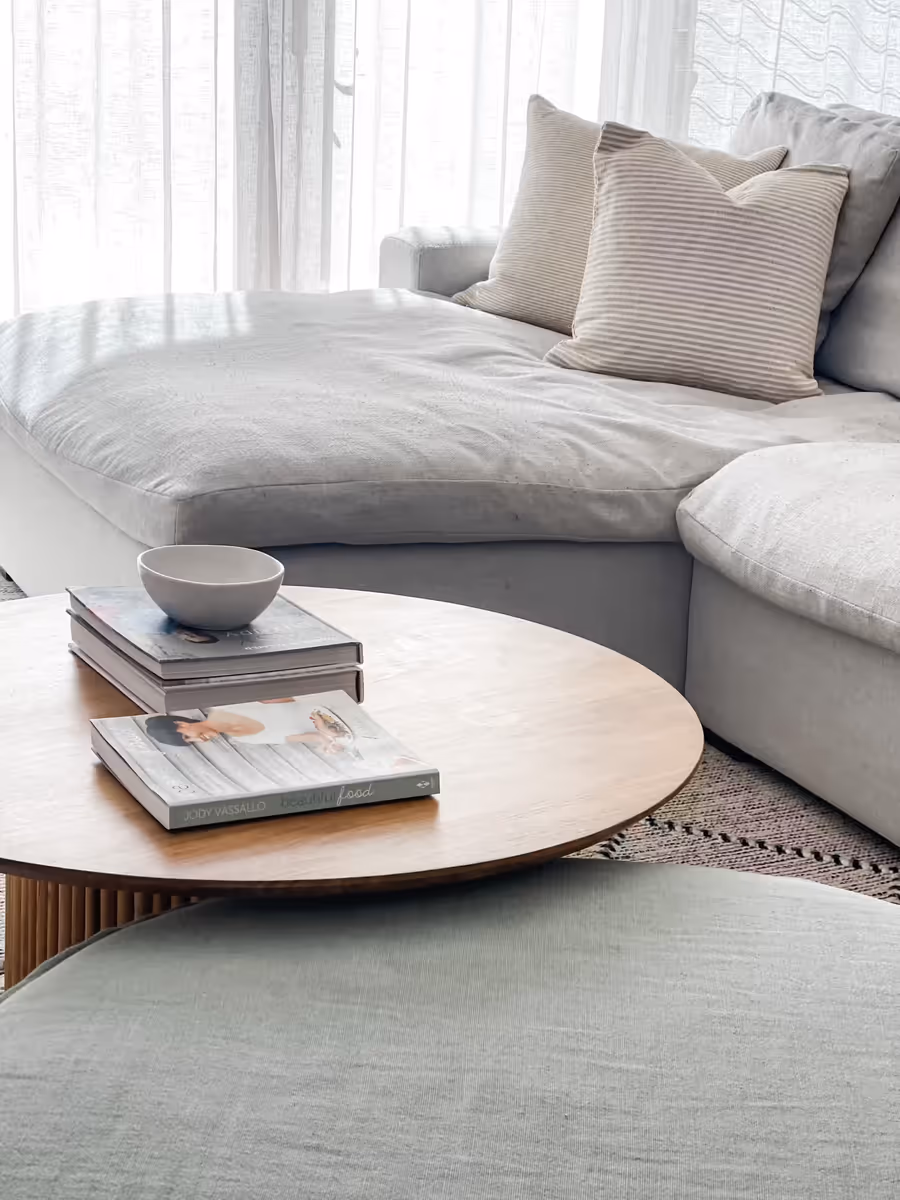 Curved grey sofa and a sage ottoman around the fluted oak coffee table