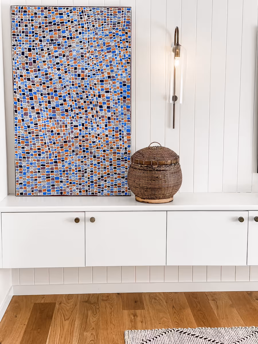 Mosaic-patterned canvas and a woven basket on the white media unit