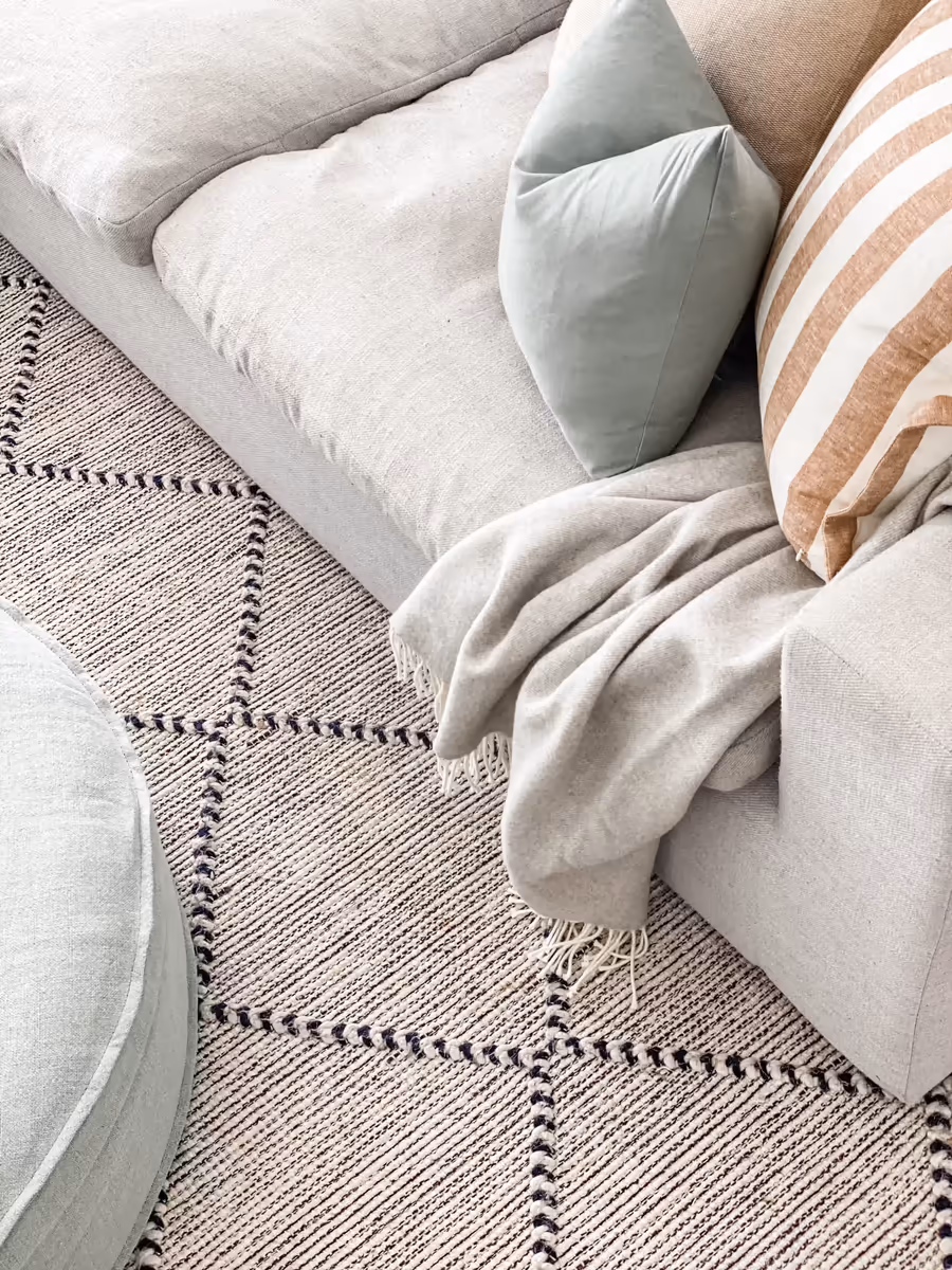 Sage and striped cushions with a linen throw draped over the corner sofa