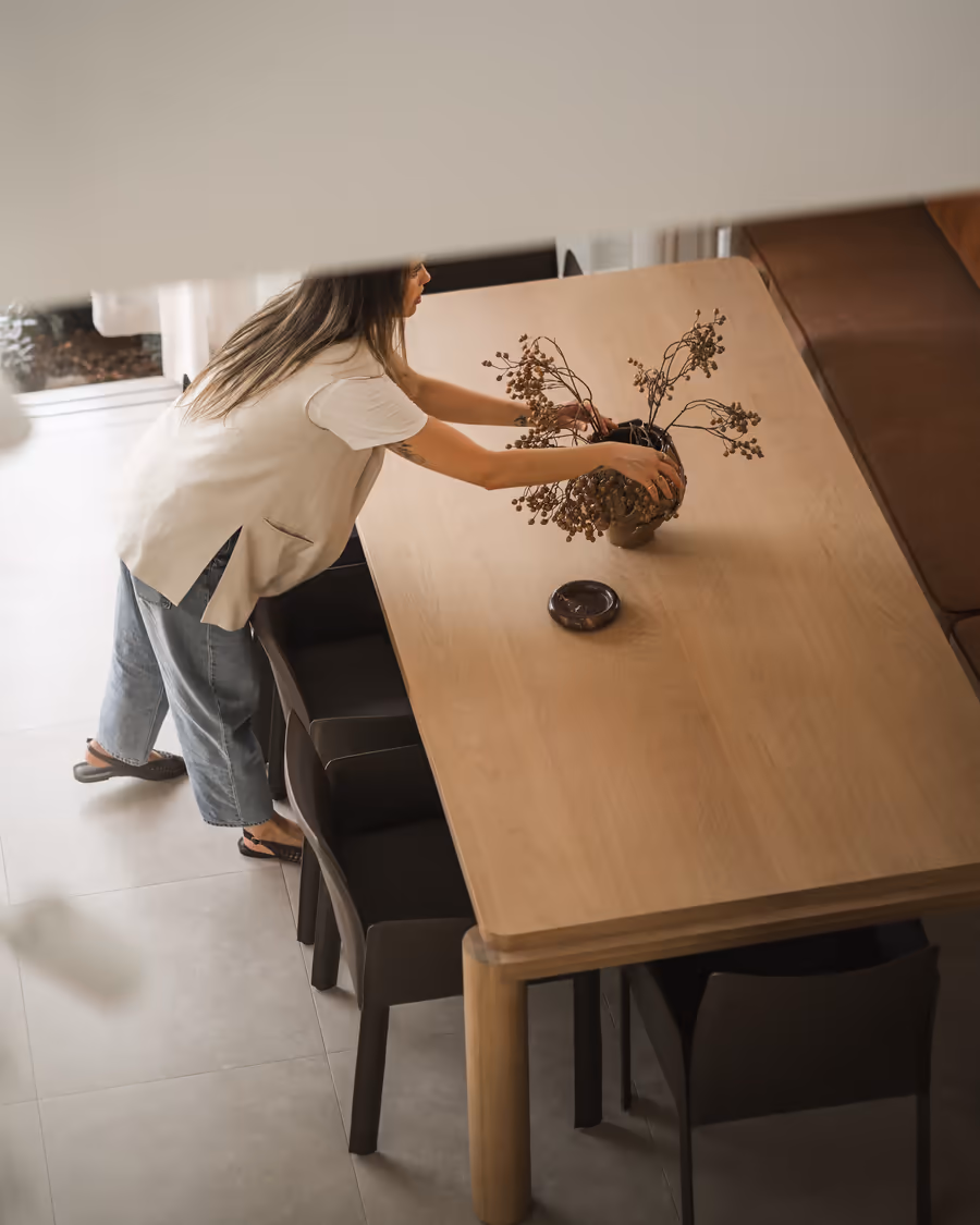 Placing dried stems in a vessel on the oak dining table