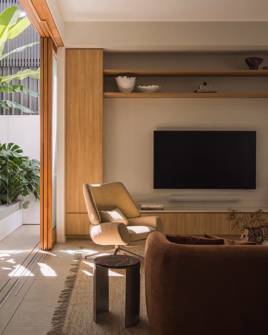 Oak joinery wall and the rust velvet sofa, doors open to the courtyard planting