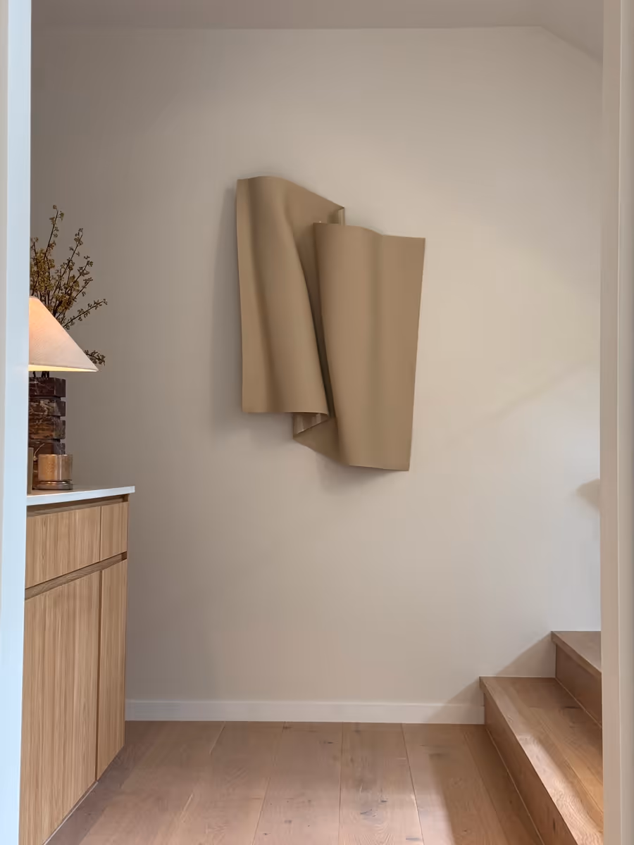 Sculptural folded wall piece above the stair, beside oak joinery