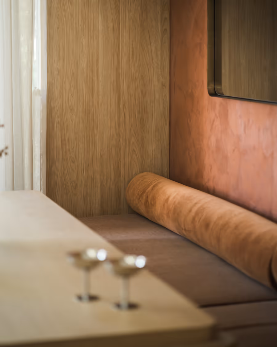 Tan leather banquette running along the oak-panelled bar, glasses set on the bench