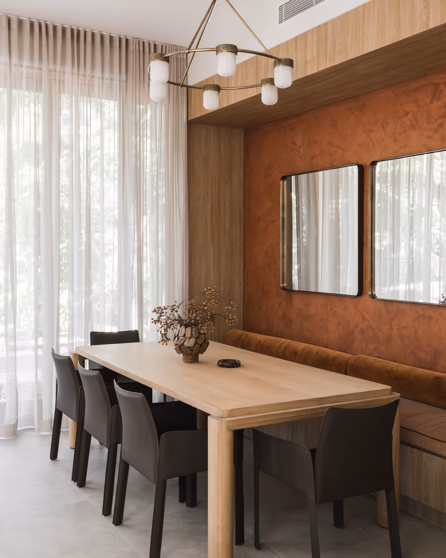Oak dining table and leather chairs against the rust limewashed wall, twin mirrors above