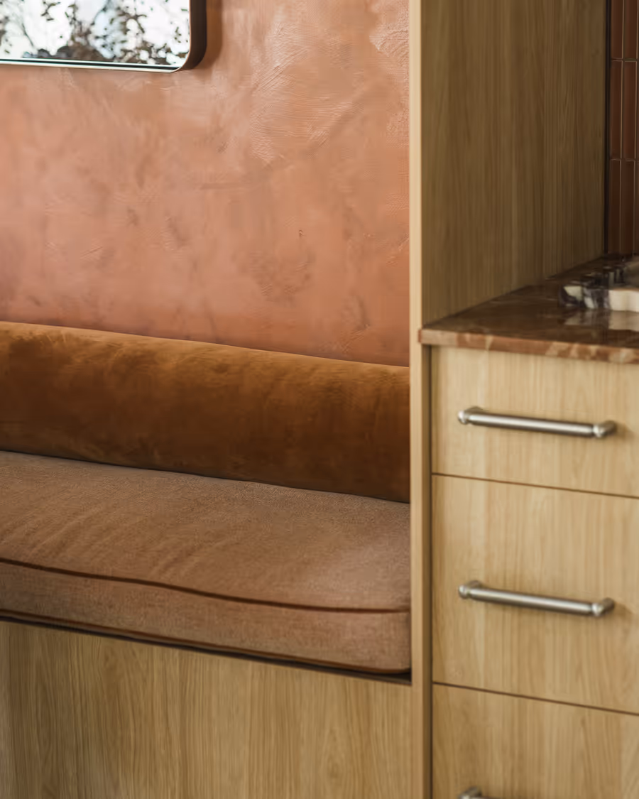 Tan leather banquette against the rust limewashed wall, beside oak joinery