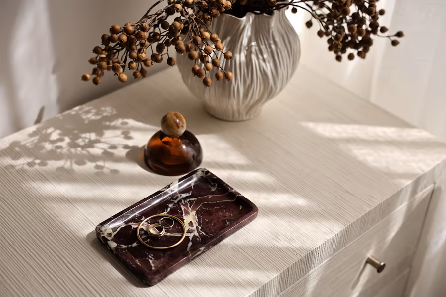 Fluted vase of dried berries and a marble tray on the bedroom chest