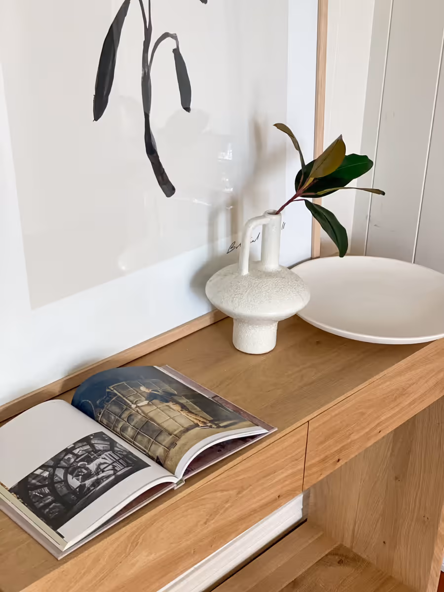 Oak console holding a ceramic lamp and an open book, below a brushstroke print