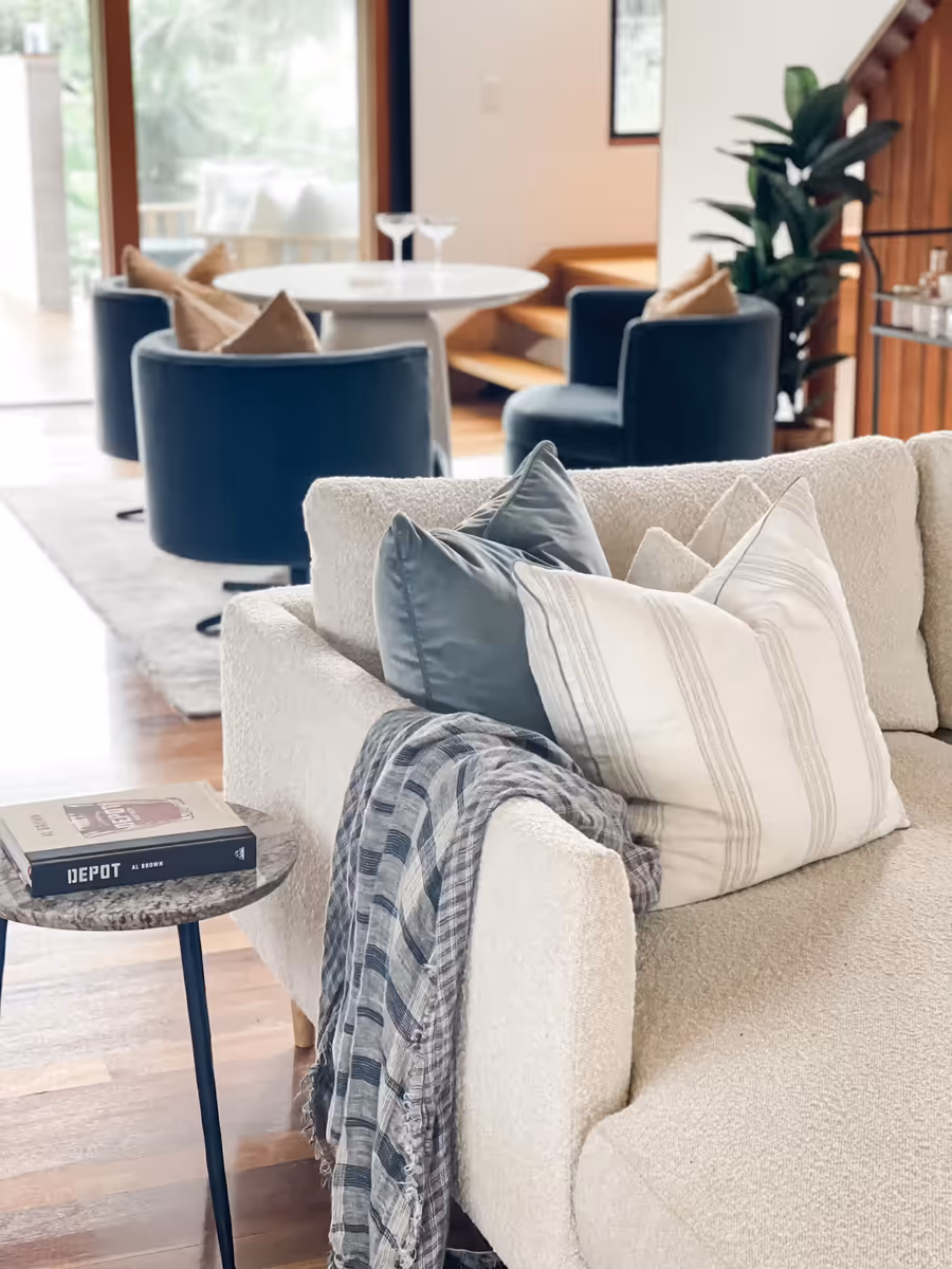 Boucle sofa with striped cushions and a throw, navy chairs and dining beyond