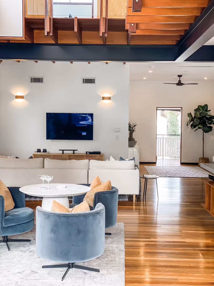 Blue velvet chairs and a white sofa in the raked living room, on polished timber floors