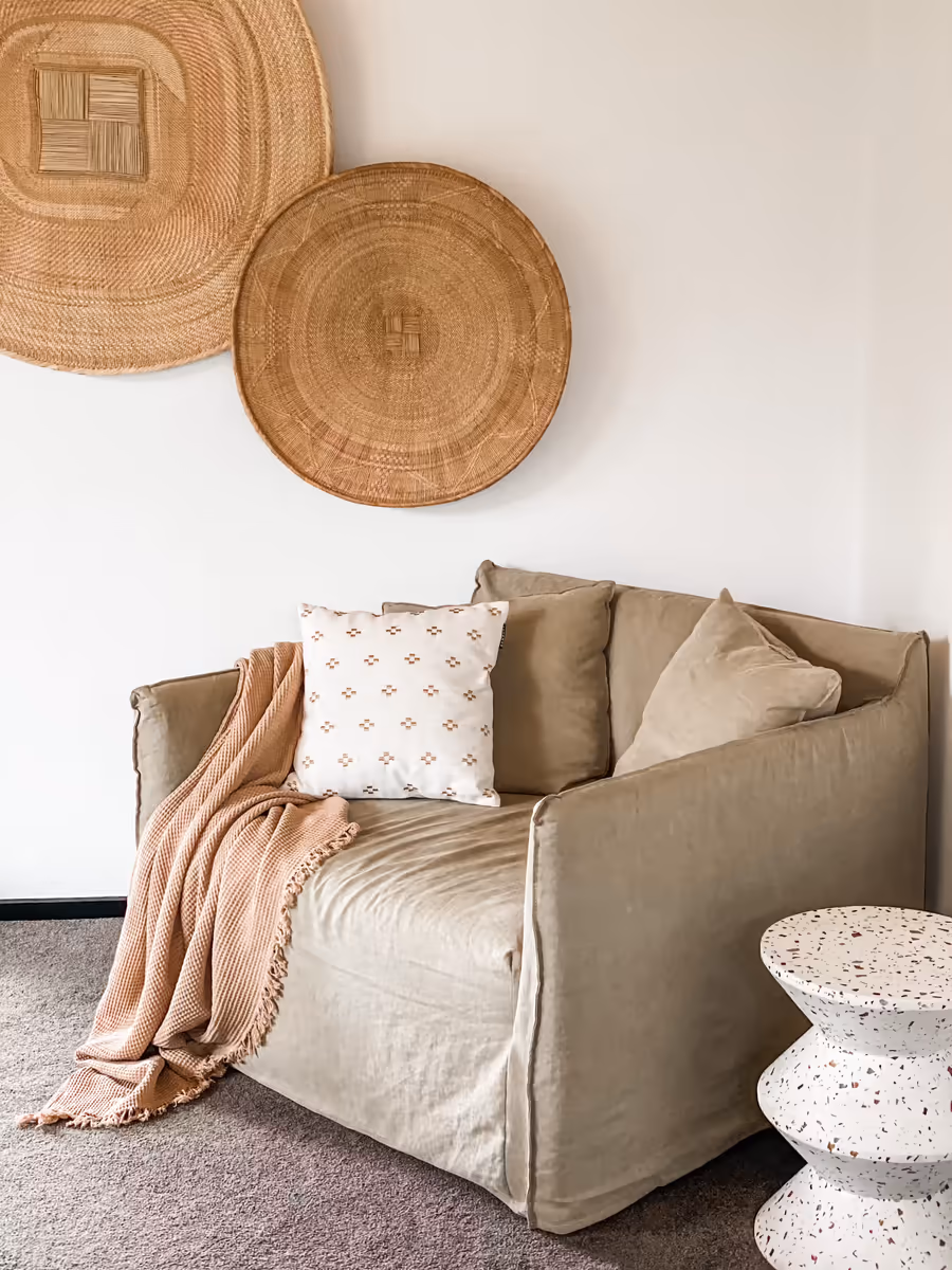 Woven discs hung above a taupe sofa layered with a blush throw